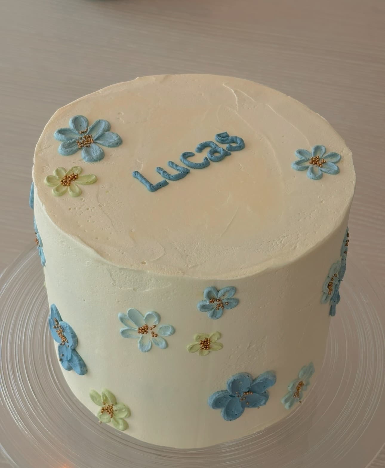 Bursdagskake med navnet Lucas, blå og grønne blomster i smørkrem